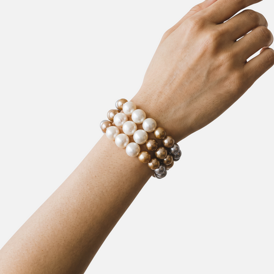 Trebor Style triple strand freshwater pearl bracelet in off-white, champagne, and soft gray on a woman's wrist.