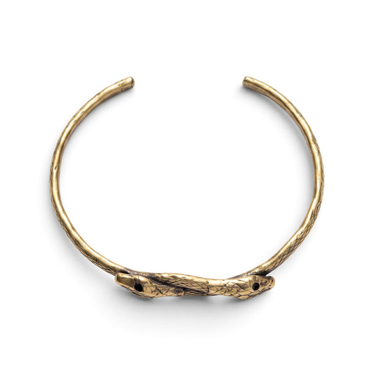 Trebor Style thin double serpent bangle in reclaimed brass with an Austrian crystal eye detail on a white background.