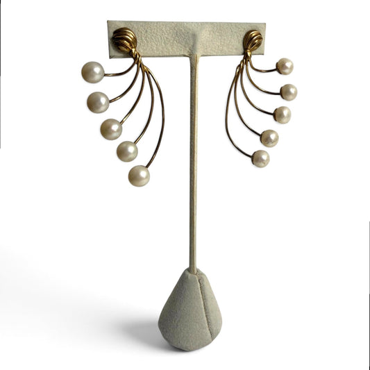 Trebor Style gold-tone fan-style statement earrings featuring cascading cream faux pearls on a display stand.
