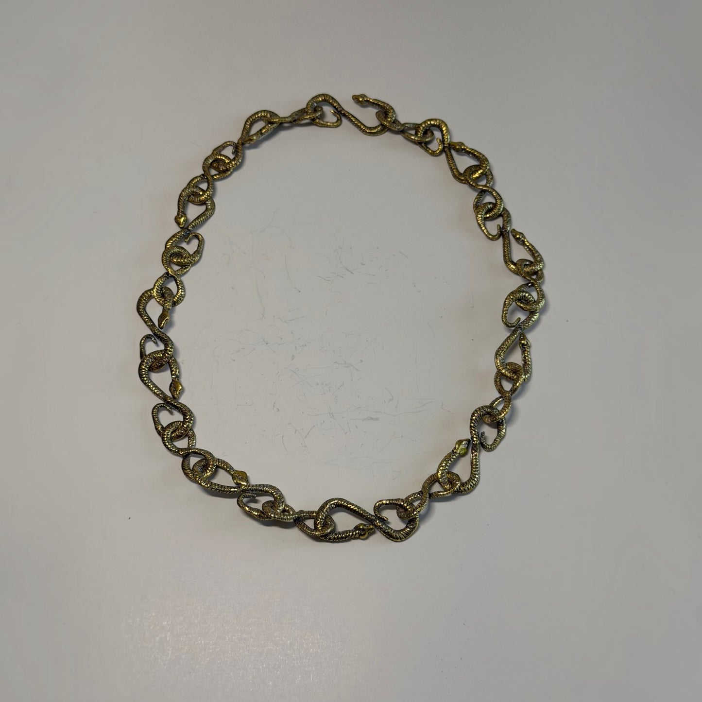 Trebor Style gold patina snake chain necklace featuring 22 interlocking snake-shaped links on a white background.