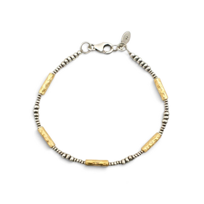Trebor Style hammered 14K vermeil tube and sterling silver bead bracelet with lobster clasp on marble background.