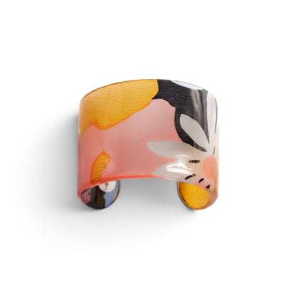 Trebor Style resin cuff bracelet featuring a vibrant abstract floral pattern in yellow, pink, and black hues.