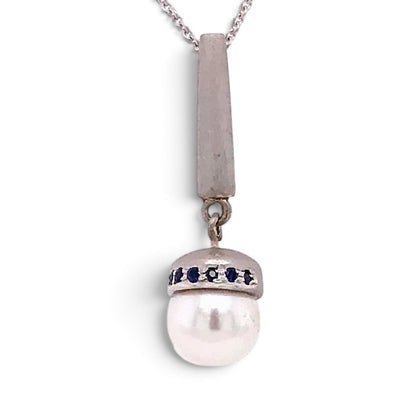 Trebor Style Akoya pearl pendant necklace with blue sapphire accents on a brushed sterling silver bale and chain.
