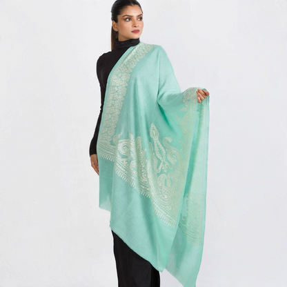 Trebor Style aqua merino wool shawl with intricate ivory embroidery worn by a model against a white background