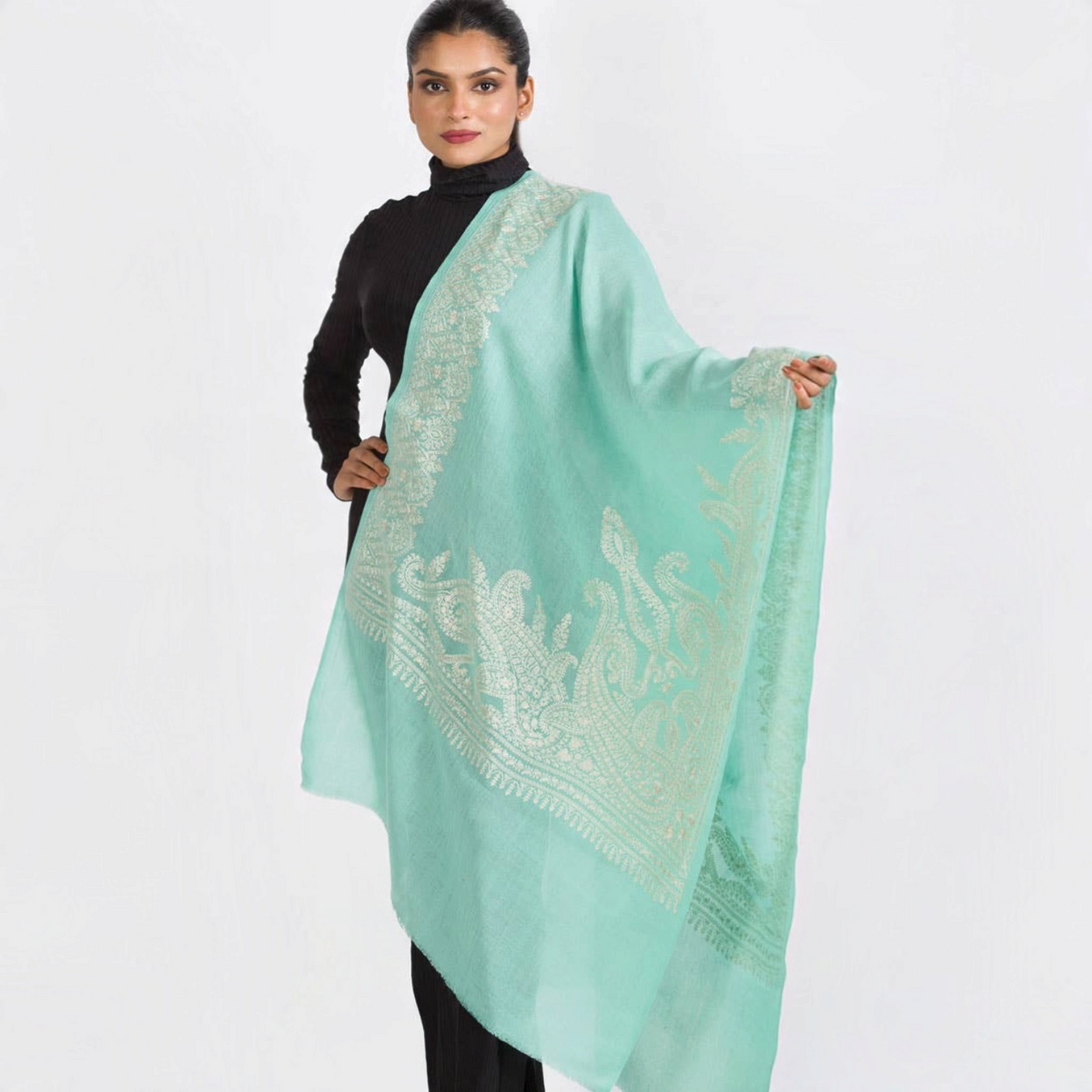 Trebor Style aqua merino wool shawl with intricate ivory embroidery draped over a model in a black turtleneck.
