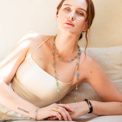 Trebor Style mixed metal necklace with sky blue aquamarine gemstones worn by a woman in a cream camisole