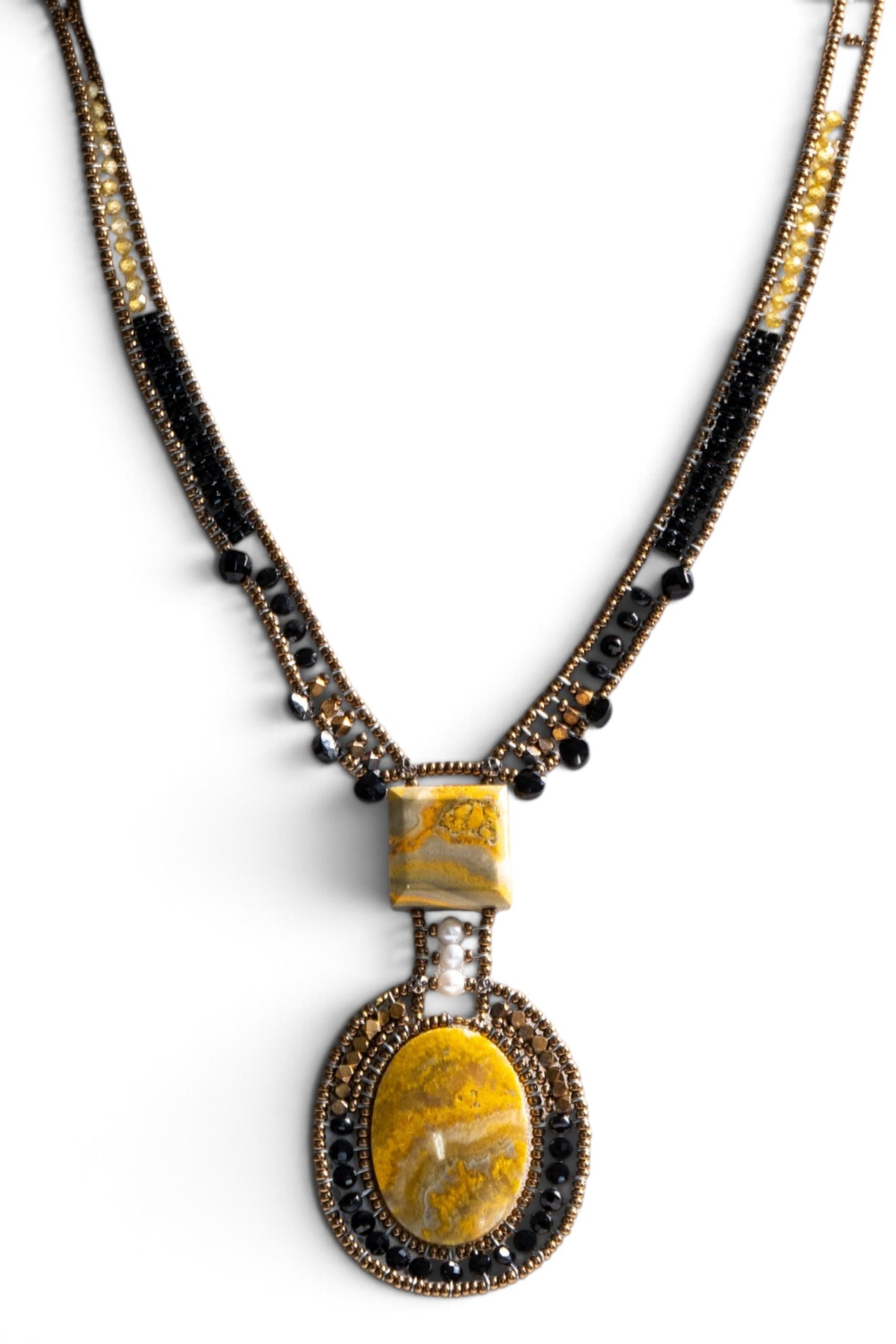 Trebor Style artisan statement necklace featuring yellow jasper, black glass beads, and a white pearl on a display bust.