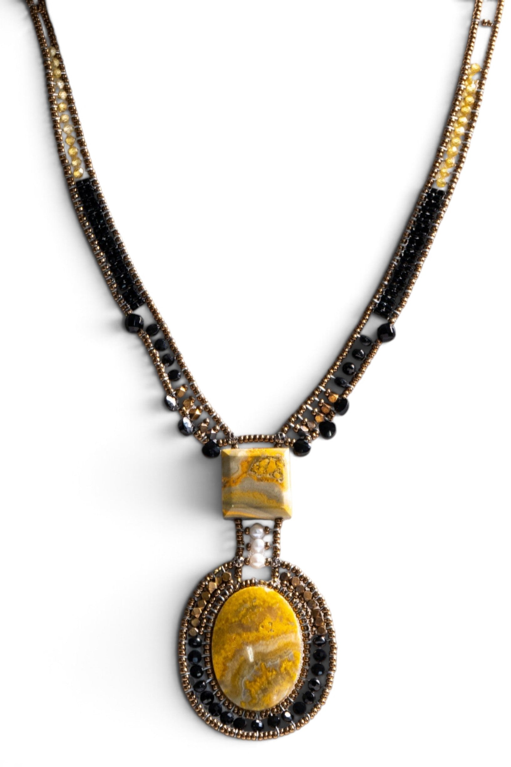 Trebor Style artisan statement necklace featuring yellow jasper, black glass beads, and a white pearl on a display bust.