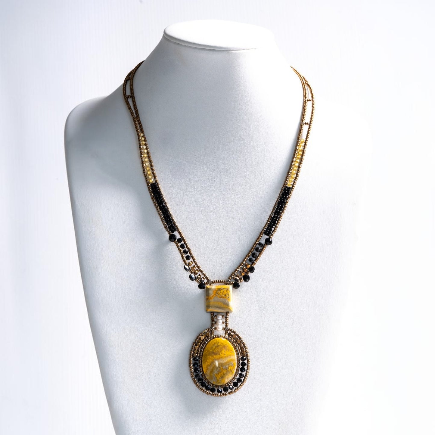 Trebor Style artisan statement necklace featuring yellow jasper, bronze, gold, and black beads with a white pearl.