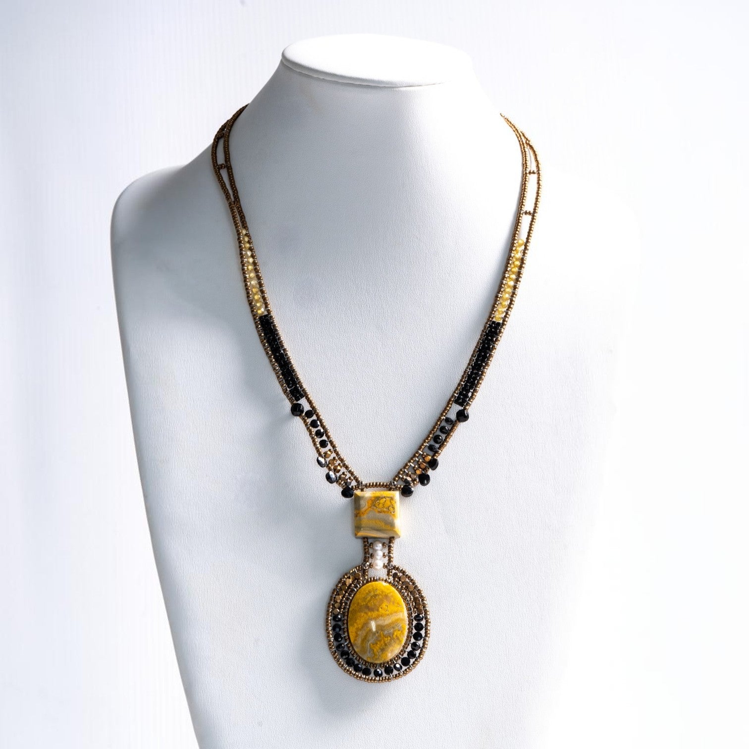 Trebor Style artisan statement necklace featuring yellow jasper, bronze, gold, and black beads with a white pearl.