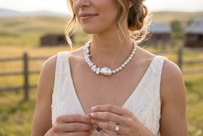 Baroque pearl necklace with mixed pearls and a central gold zircon anchor in sunlit outdoors.