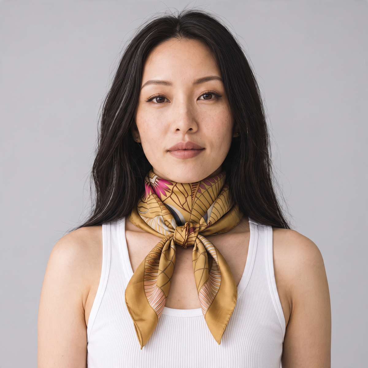 Trebor Style beige silk crepe square scarf with jungle print in gold, pink, and blue worn by a woman.