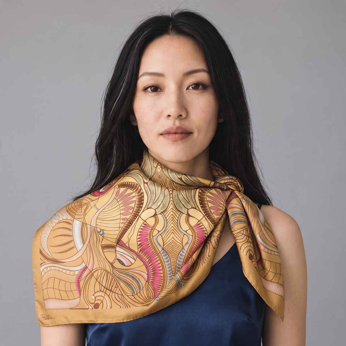 Trebor Style beige silk crepe square scarf with jungle print in gold, pink, and blue worn by a woman.
