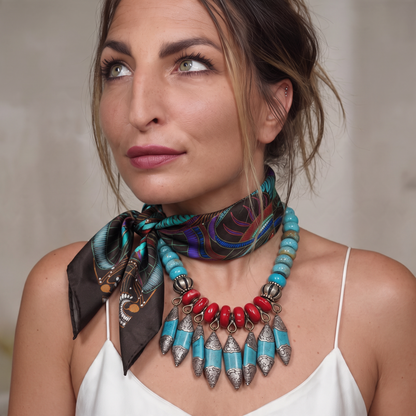 Trebor Style black silk satin tube scarf with jungle print worn by a woman with a turquoise and red statement necklace