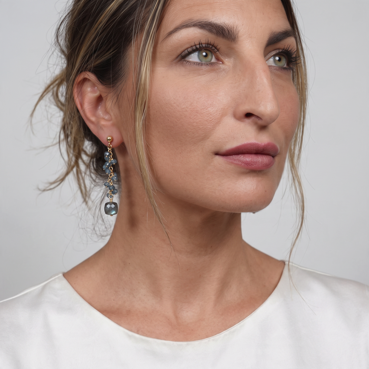 Trebor Style London Blue Topaz and cubed Labradorite drop earrings on gold filled sterling wire worn by a woman.
