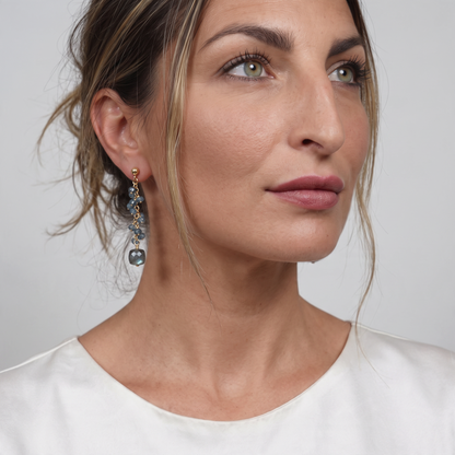 Trebor Style London Blue Topaz and cubed Labradorite drop earrings on gold filled sterling wire worn by a woman.