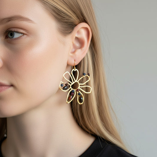 Trebor Style boho brass flower earrings featuring black opals, rubies, and sapphires worn by a woman.