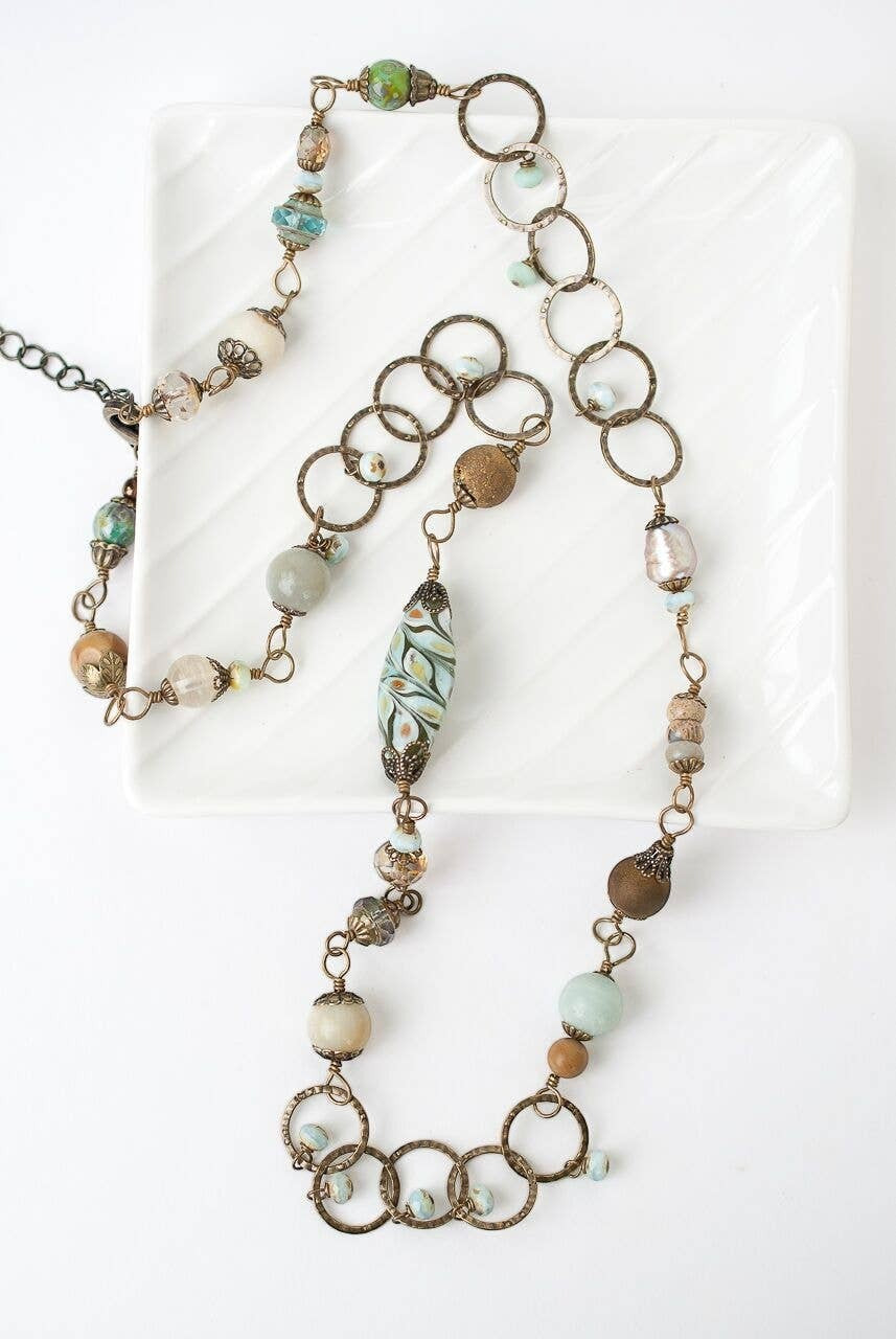 Trebor Style collage necklace featuring antique brass rings, Czech glass beads, and gemstones in earthy tones.