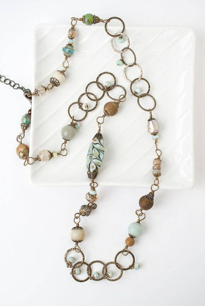 Trebor Style collage necklace featuring antique brass rings, Czech glass beads, and gemstones in earthy tones.