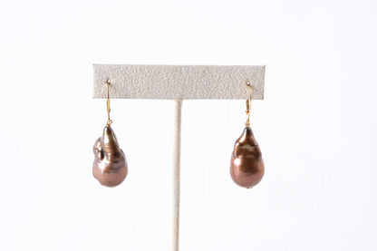 Trebor Style bronze baroque pearl drop earrings with 18k gold lever backs on a display stand.