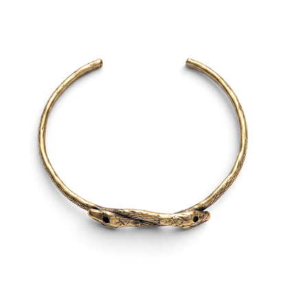 Trebor Style thin double serpent bangle in reclaimed brass with an Austrian crystal eye detail on a white background.