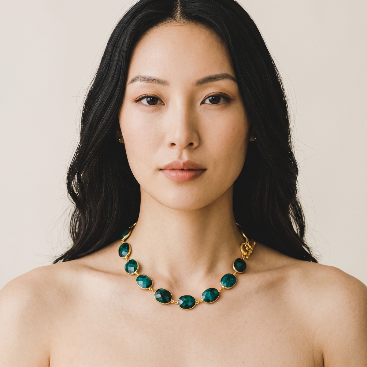 Trebor Style faceted emerald bezel-set toggle necklace worn by a woman with long dark hair against a neutral background