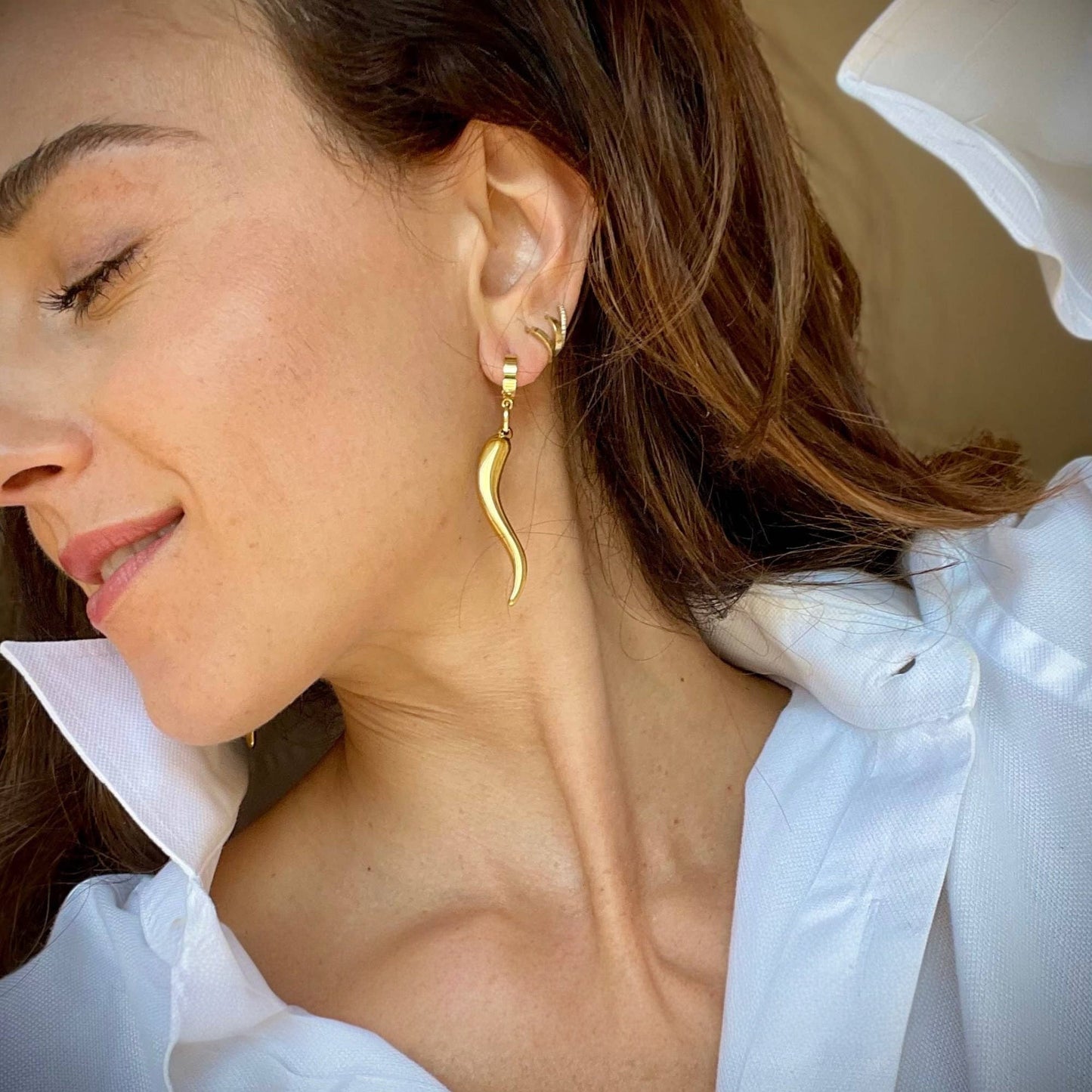 Trebor Style gold chili pepper charm hoop earrings worn by a woman in a white collared shirt