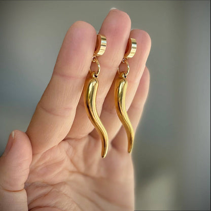 Trebor Style gold-filled chili pepper charms dangling from sleek stainless steel hoop earrings held in a hand.