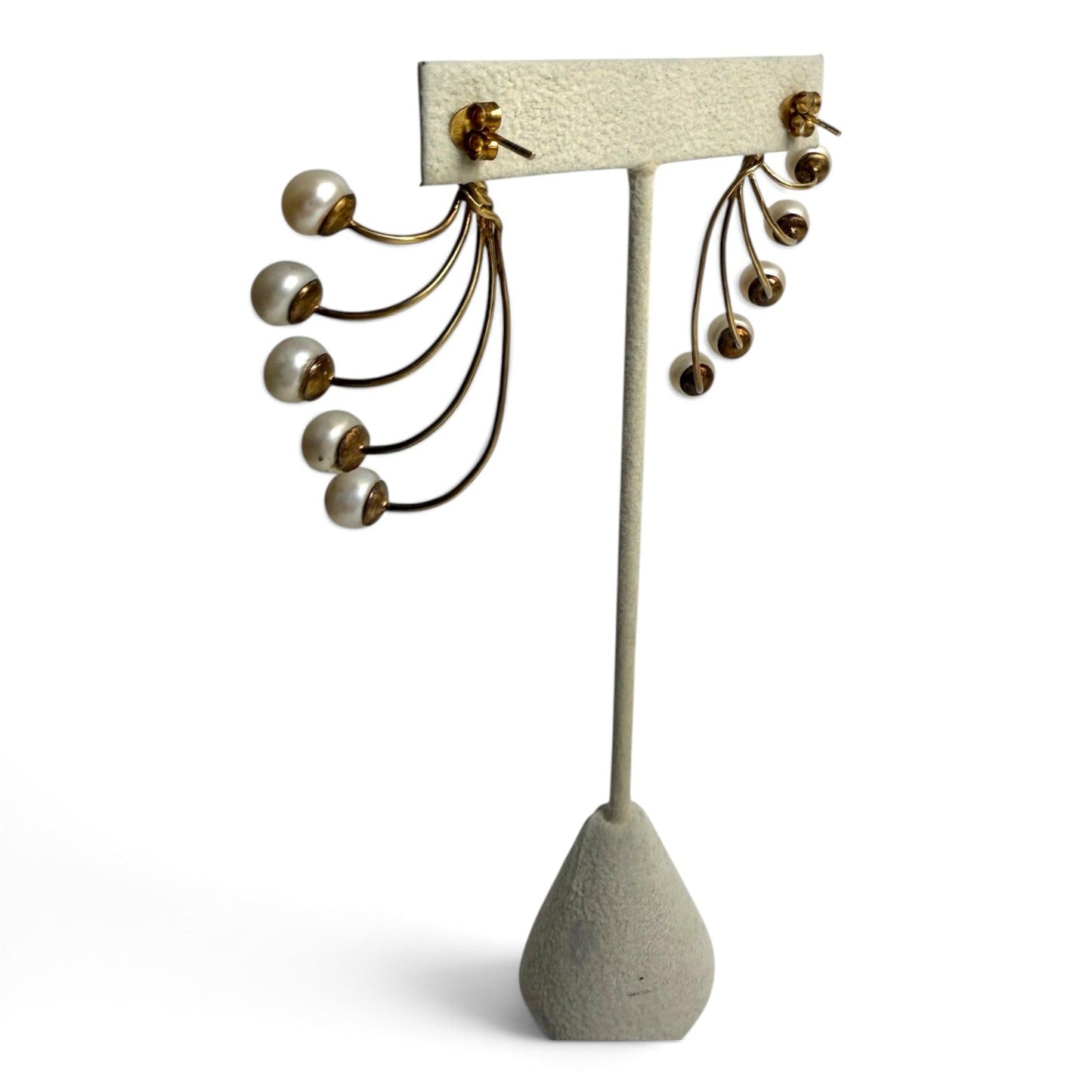 Trebor Style gold-tone fan-style statement earrings featuring five cascading cream faux pearls on a display stand.