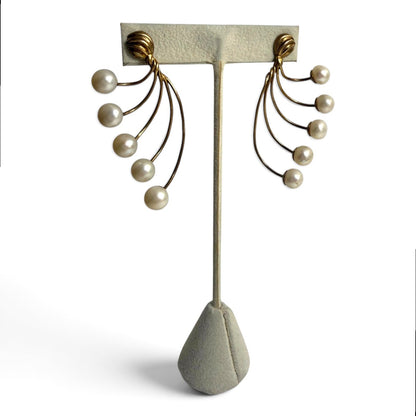 Trebor Style gold-tone fan-style statement earrings featuring cascading cream faux pearls on a display stand.