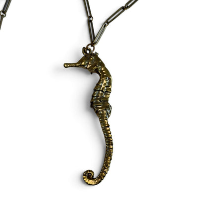Trebor Style seahorse necklace in gold patina with an intricate link chain, symbolizing oceanic grace and strength.