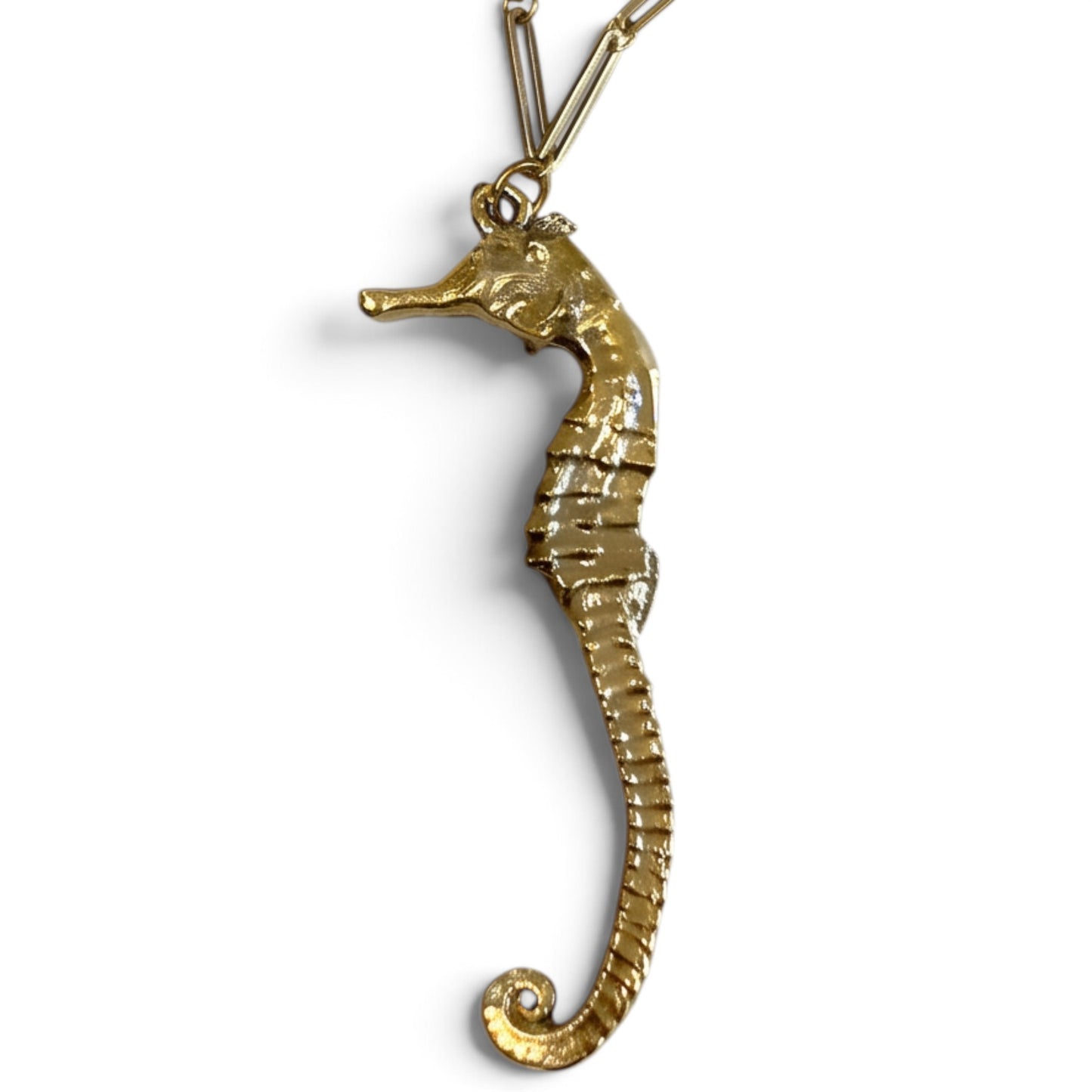 Trebor Style gold seahorse necklace with intricate textured detail and a delicate leaf clasp on a gold chain.