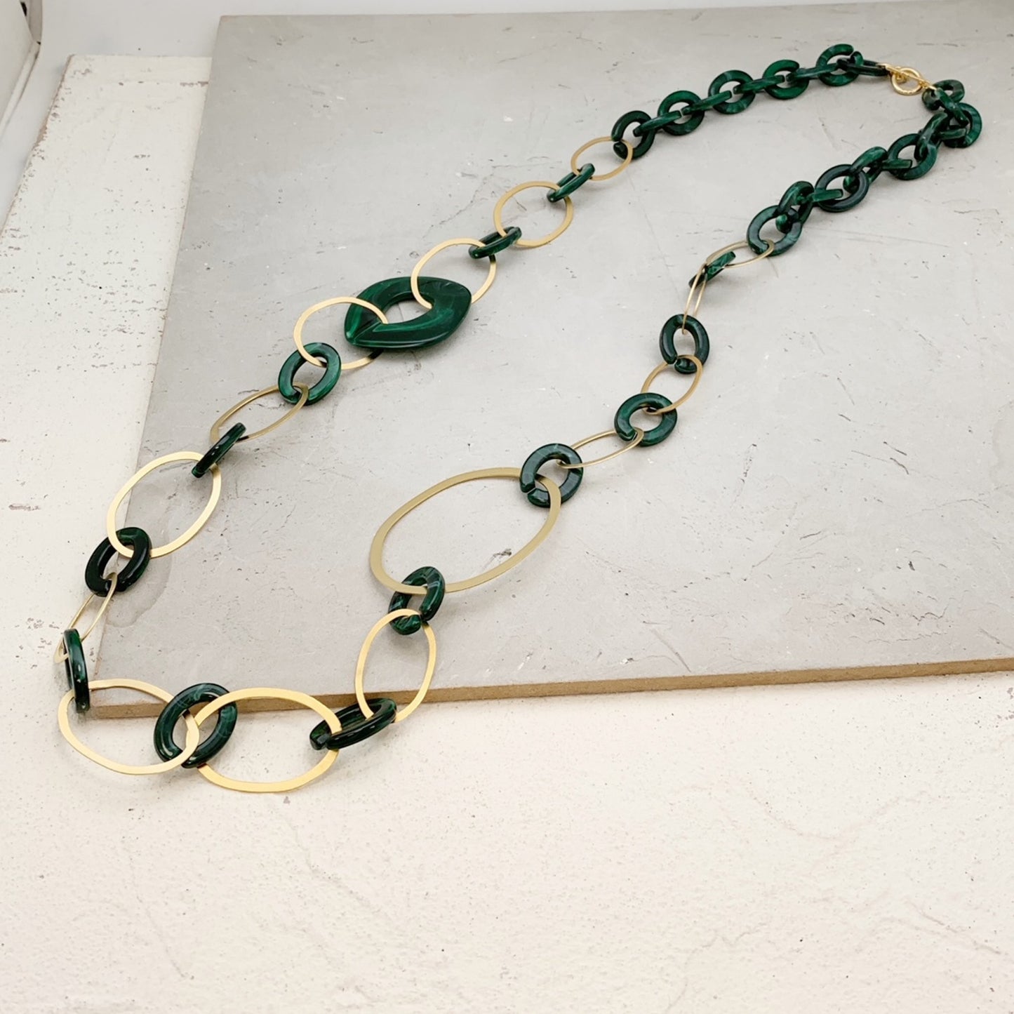 Trebor Style long necklace featuring dark green acrylic links and 24k gold-plated oval metal accents.