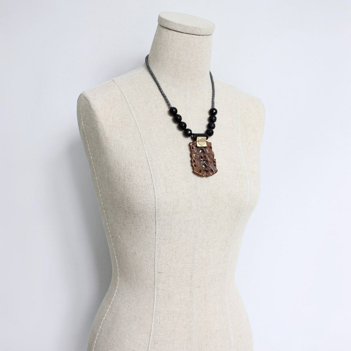 Trebor Style carved jade and black agate pendant necklace with hematite beads on a mannequin display