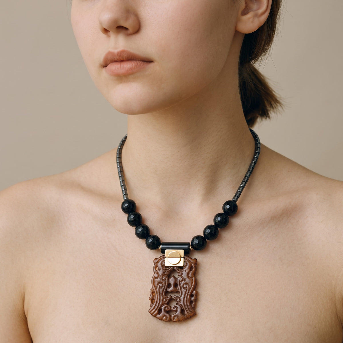 Trebor Style necklace featuring a carved jade pendant, black agate beads, and hematite accents on a beaded chain.