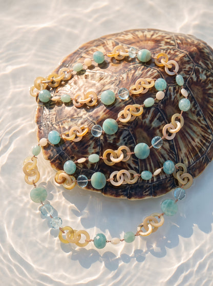 Trebor Style long necklace featuring tan horn, turquoise chalcedony, crystal, and pearl beads on rose gold chain links.