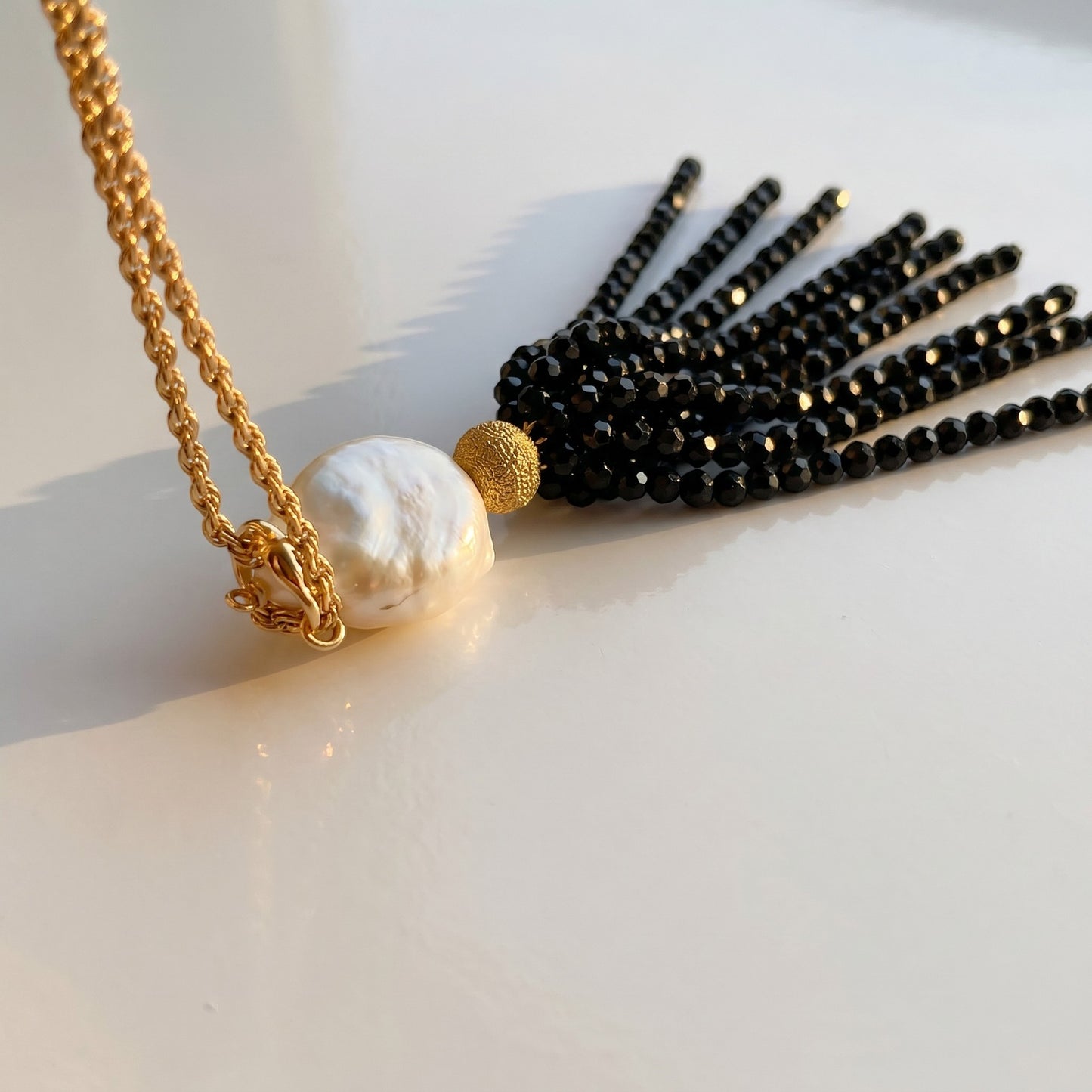 Trebor Style necklace featuring a white Mabe pearl and black spinel gemstone tassel on a gold-filled chain.