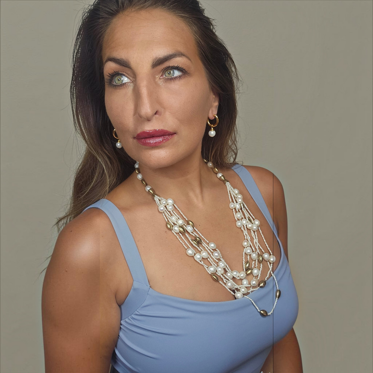 Trebor Style multi-strand freshwater pearl and 14k gold plated bead necklace worn by a woman in a blue top