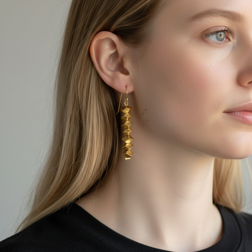 Trebor Style Nael dangle earrings featuring geometric 24k gold plated beads worn by a woman