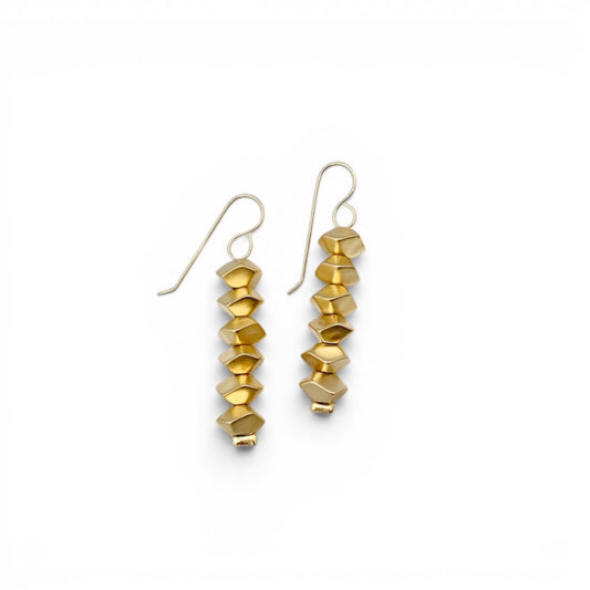 Trebor Style Nael dangle earrings featuring geometric 24k gold plated beads on a textured stone display
