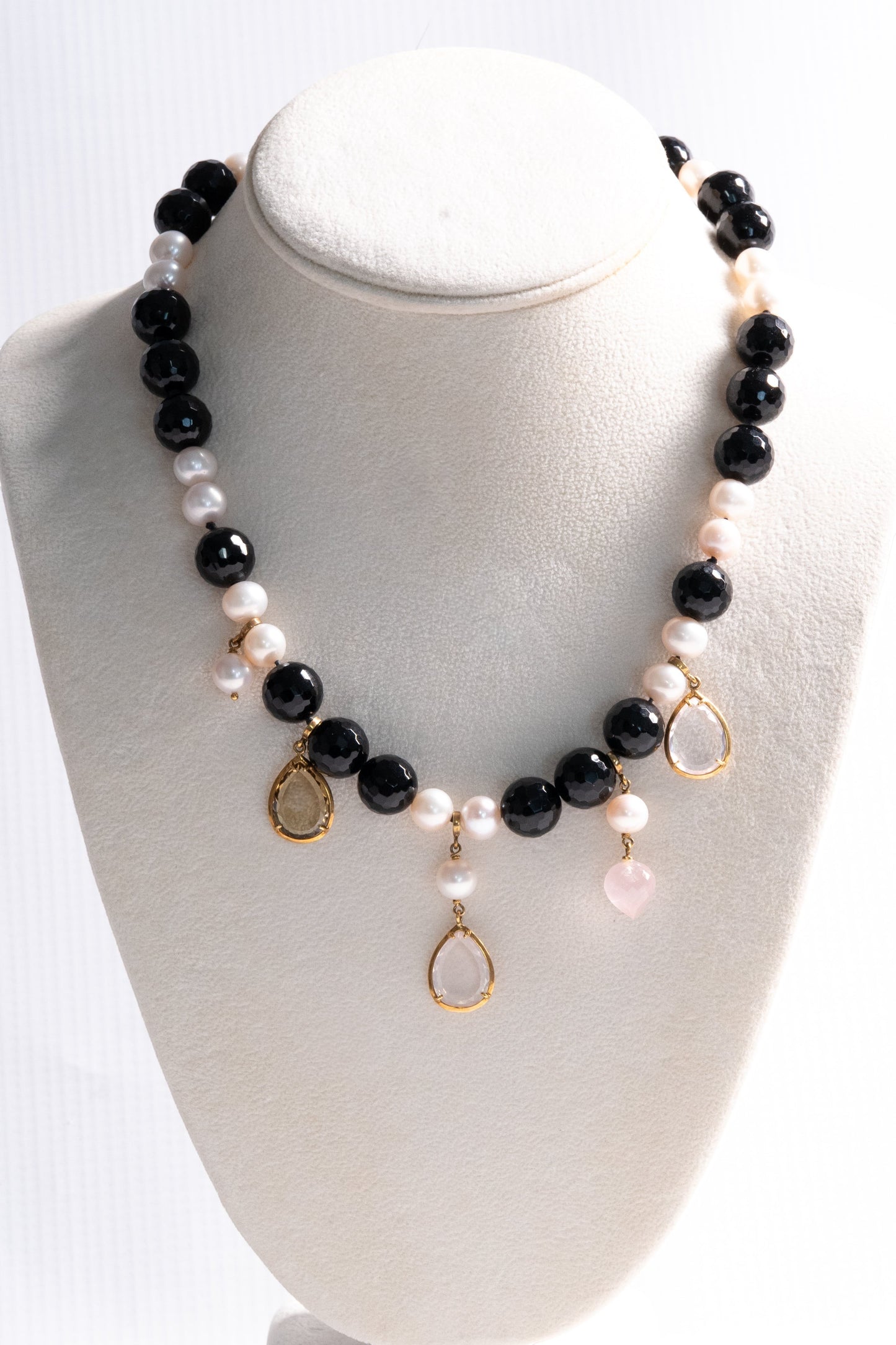 Trebor Style 18k gold necklace featuring black onyx beads, white pearls, and quartz charm drops on a display bust.