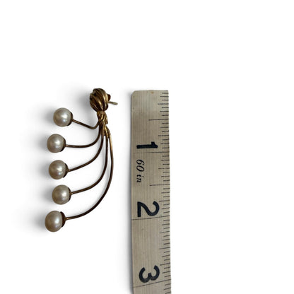 Trebor Style gold-tone fan-style statement earrings with five cream faux pearls, shown next to a measuring tape.