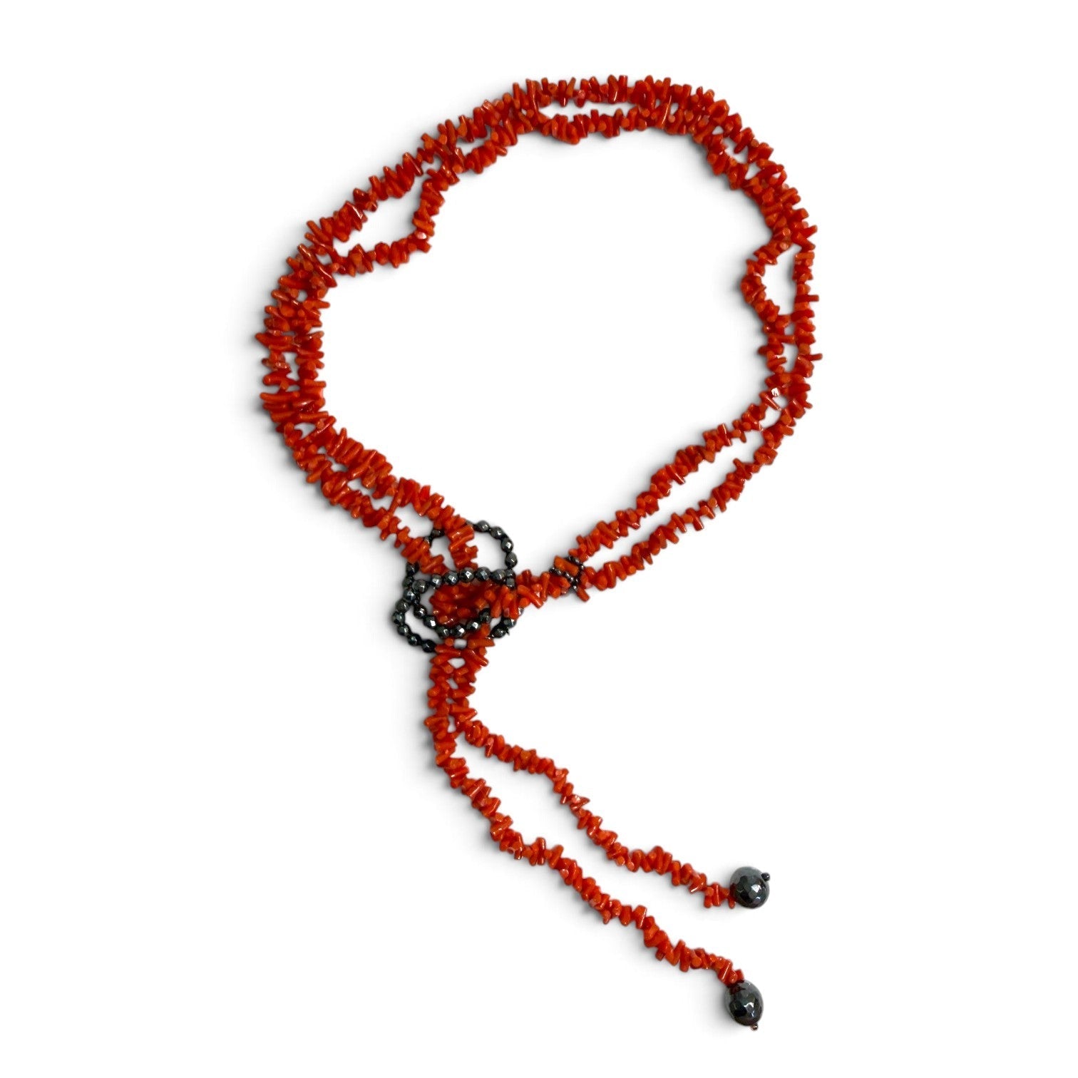 Trebor Style RAJOLA multi-strand necklace featuring red coral chips and dark faceted hematite beads on a white surface