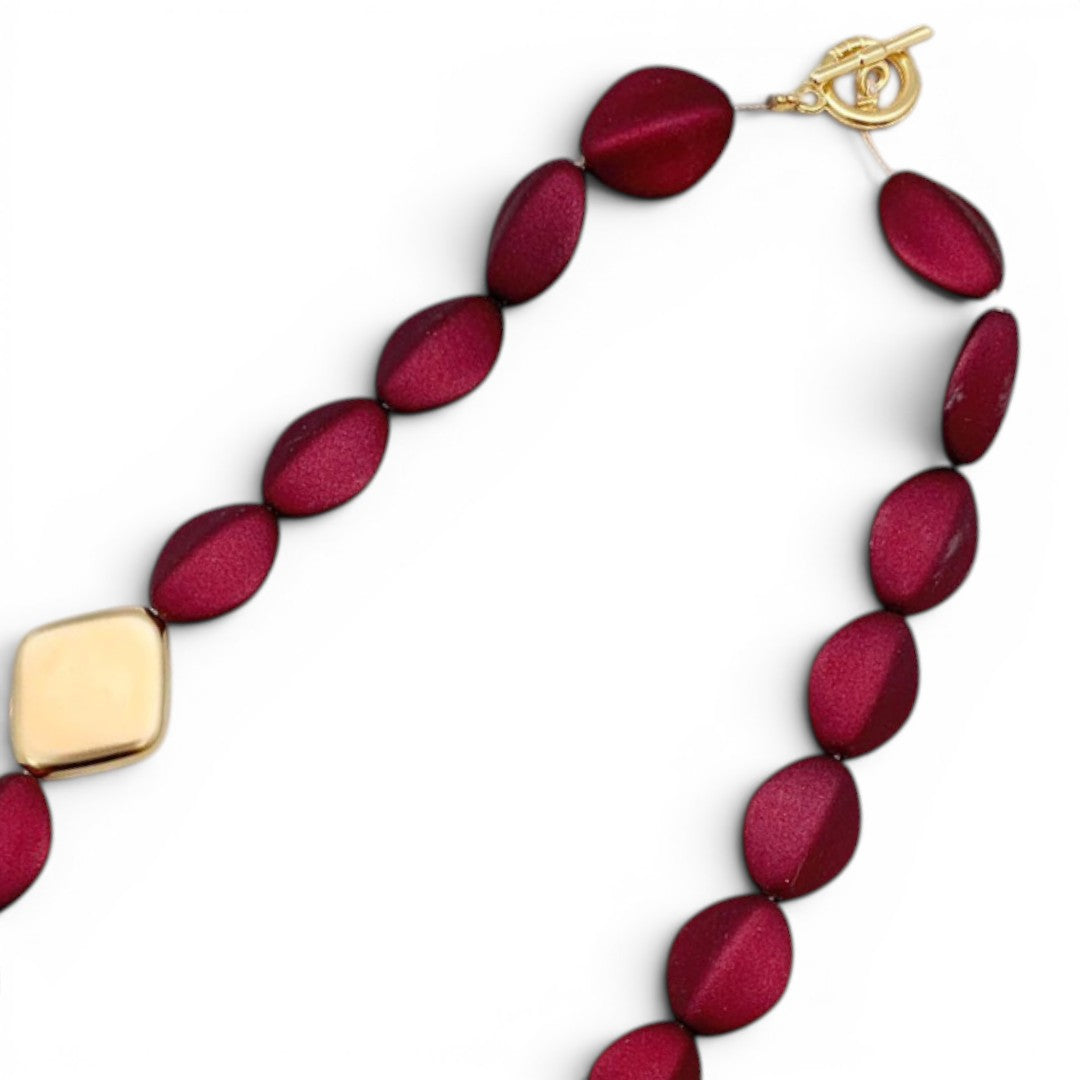 Trebor Style Loni statement necklace with dark red oval acrylic beads and diamond-shaped 24k gold-plated metal beads.
