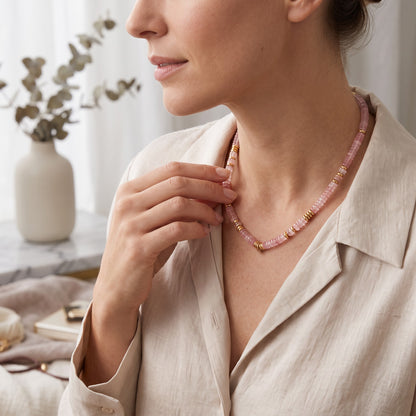 Trebor Style rose quartz heishi bead necklace with gold-plated accents worn by a woman in a beige linen shirt.