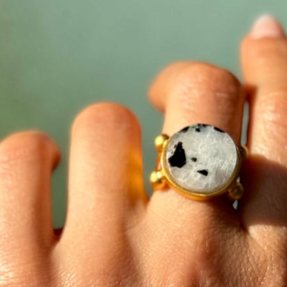 Trebor Style 16mm round moonstone ring with black inclusions set in a chunky gold filled adjustable band on a finger