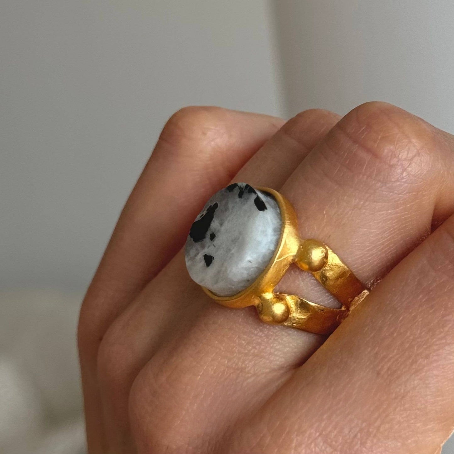 Trebor Style 16mm round moonstone ring with black inclusions set in a chunky gold filled adjustable band on a finger