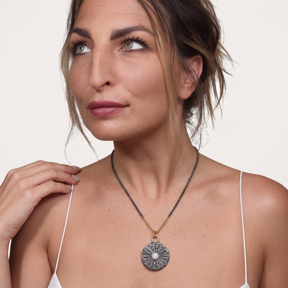 Trebor Style sand dollar pendant necklace in oxidized sterling silver and 14k gold with white sapphires on a model
