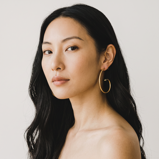 Trebor Style serpent hoop earrings in reclaimed metal worn by a woman with long dark hair against a neutral background
