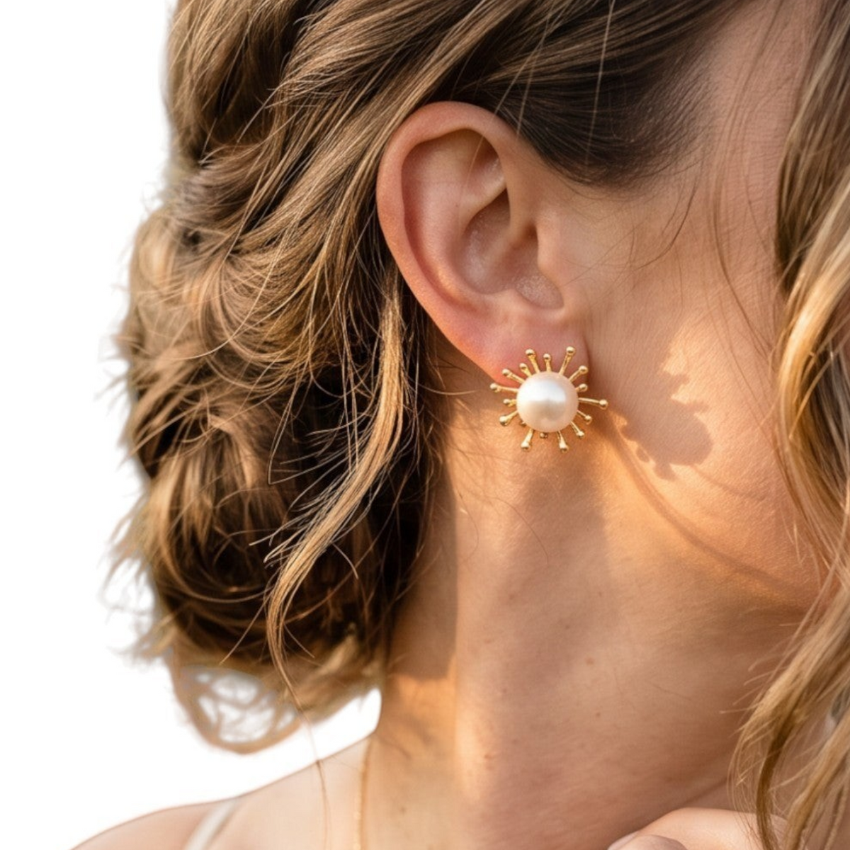 Trebor Style 14k yellow gold sunburst stud earrings featuring a white Japanese Akoya cultured pearl on a woman